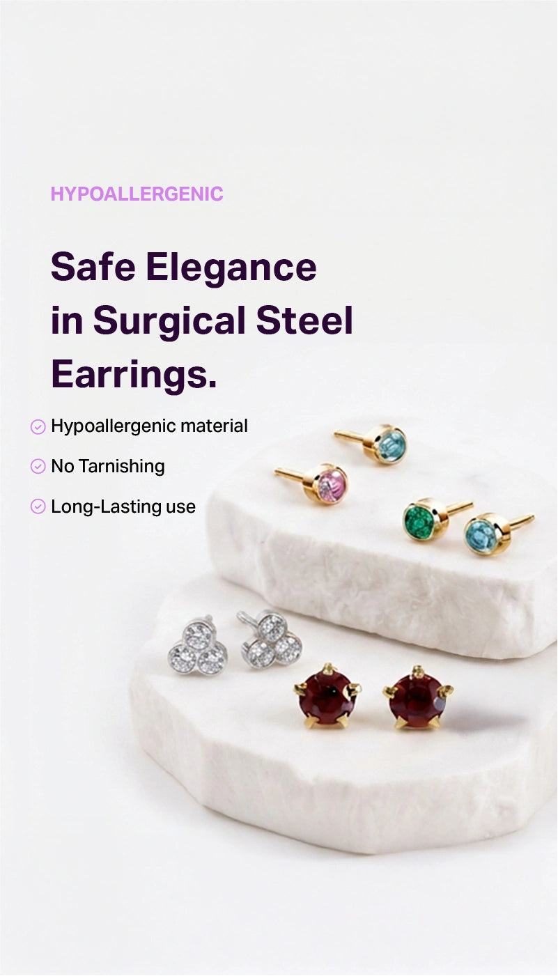 Promotional product image for surgical steel earrings on a clean white background with marketing text. Several pairs of stud earrings are displayed on white stone slabs, including gold settings with pink, green, blue, silver, and burgundy stones.